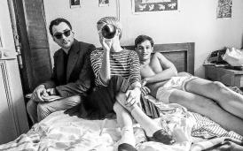 Photo en noir & blanc. Trois personnes assises sur un lit. Extrait du Film "Nouvelle Vague" 2025.