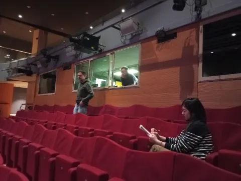 Trois hommes dans les gradins rouges d'une salle de spectacle